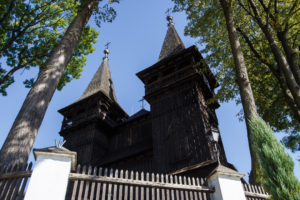 Widok z żabiej perspektywy na wieże drewnianego kościoła w Krzęcinie.