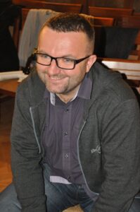Na zdjęciu Andrzej Morawa, reżyser Teatru Maska. Usmiechnięty, krótko obcięty szatyn w okularach.
